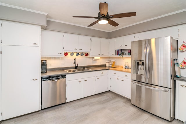 kitchen with a ceiling fan, a sink, ornamental molding, stainless steel appliances, and white cabinetry