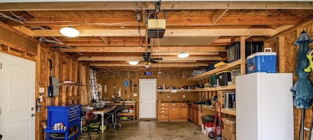 garage with a workshop area, a garage door opener, and ceiling fan