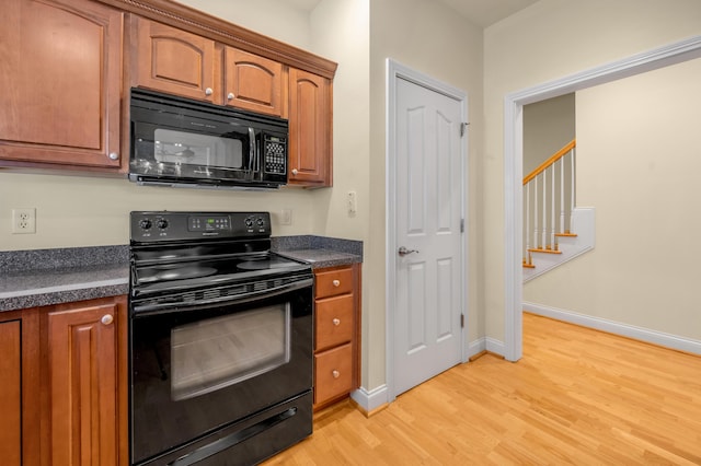 kitchen with black appliances, light wood-type flooring, dark countertops, and brown cabinetry