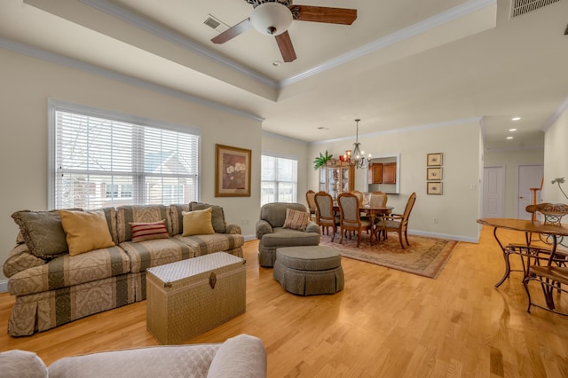 living area with light wood finished floors, visible vents, and a tray ceiling