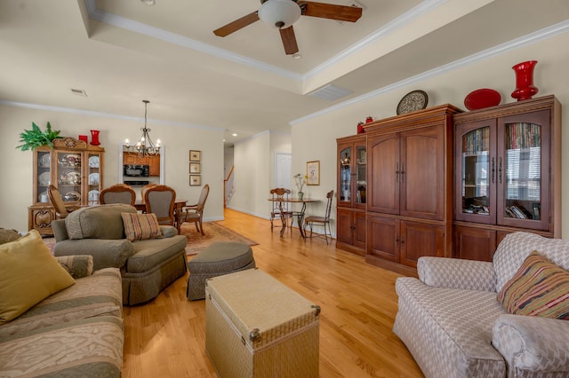 living room featuring ornamental molding, light wood-type flooring, a raised ceiling, and visible vents