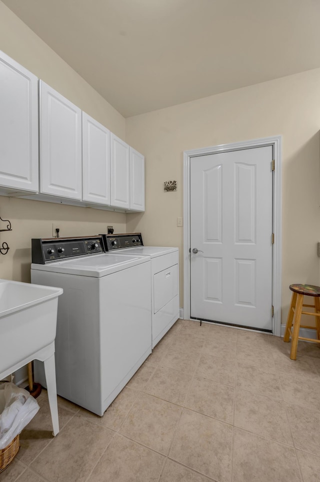 washroom with cabinet space, washing machine and dryer, and light tile patterned flooring