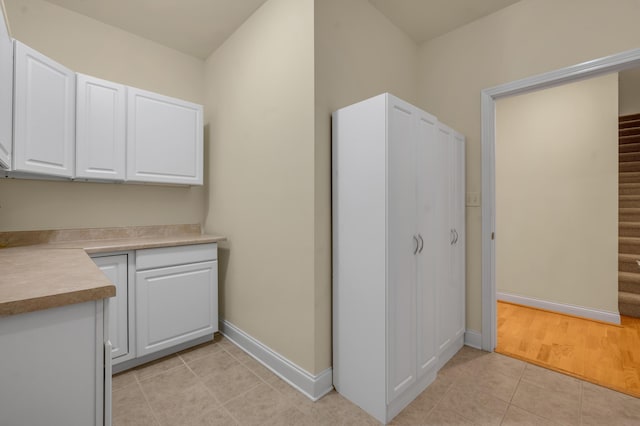 kitchen featuring light tile patterned floors, baseboards, white cabinetry, and light countertops