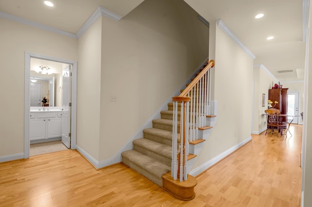 staircase featuring crown molding, baseboards, and wood finished floors