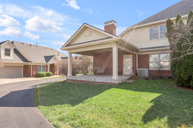 view of front of house with central AC, brick siding, driveway, a chimney, and a front yard