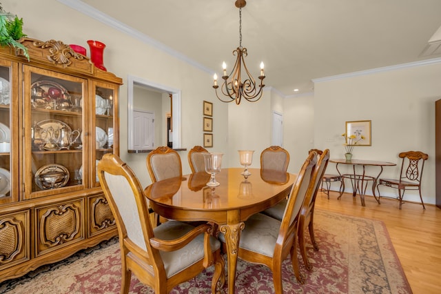 dining area with a chandelier, ornamental molding, and light wood-style flooring