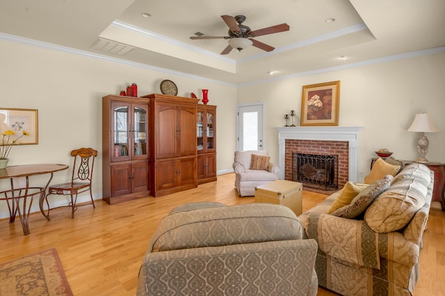 living area with light wood-style floors, a raised ceiling, and ornamental molding