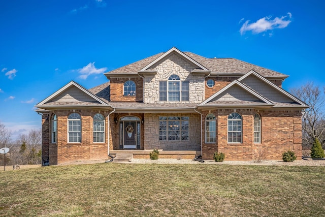 view of front of property featuring brick siding, a shingled roof, stone siding, and a front yard