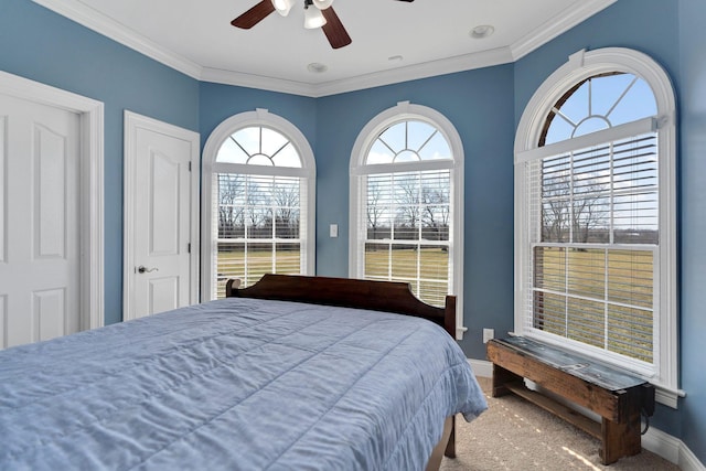 carpeted bedroom with crown molding, baseboards, and ceiling fan