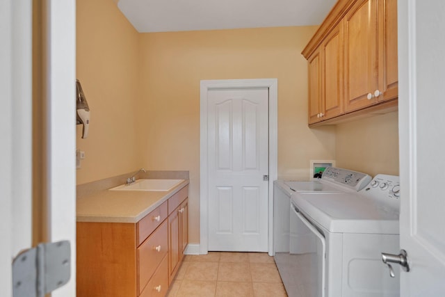 washroom featuring light tile patterned floors, washing machine and dryer, a sink, and cabinet space