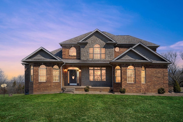 view of front of home featuring stone siding, brick siding, a lawn, and a shingled roof