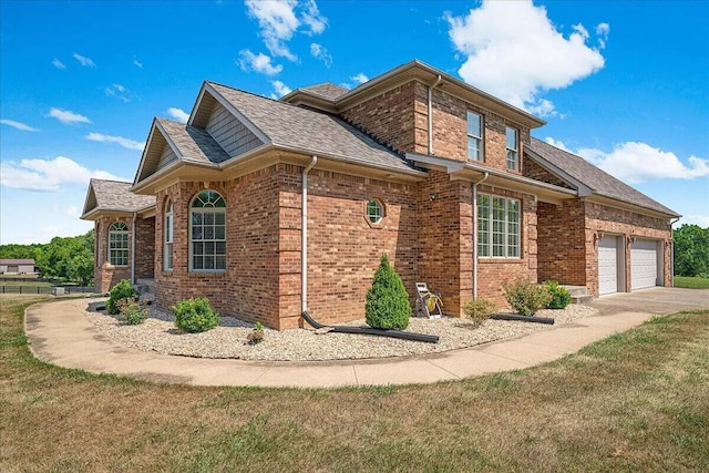 view of property exterior featuring an attached garage, brick siding, a shingled roof, a yard, and driveway