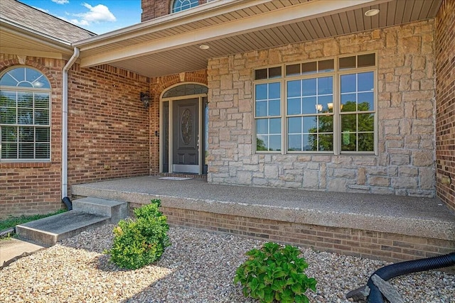 property entrance featuring a porch, stone siding, and brick siding