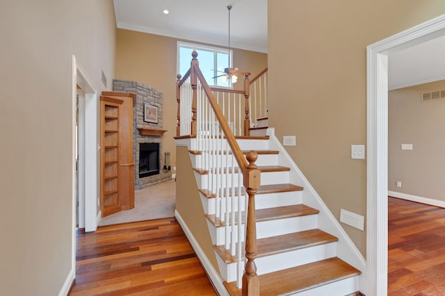 staircase featuring visible vents, crown molding, baseboards, and wood finished floors