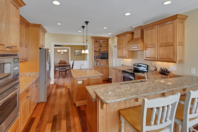 kitchen with a kitchen island with sink, a peninsula, premium range hood, a sink, and appliances with stainless steel finishes