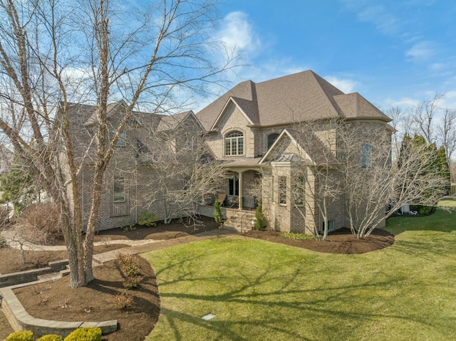 french provincial home featuring brick siding, a shingled roof, and a front lawn