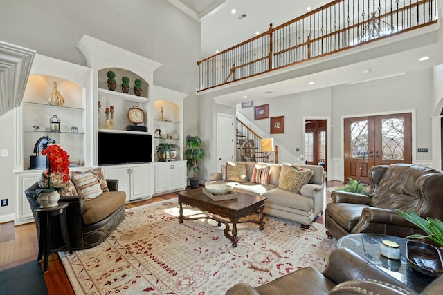 living room with built in features, stairs, ornamental molding, french doors, and wood finished floors