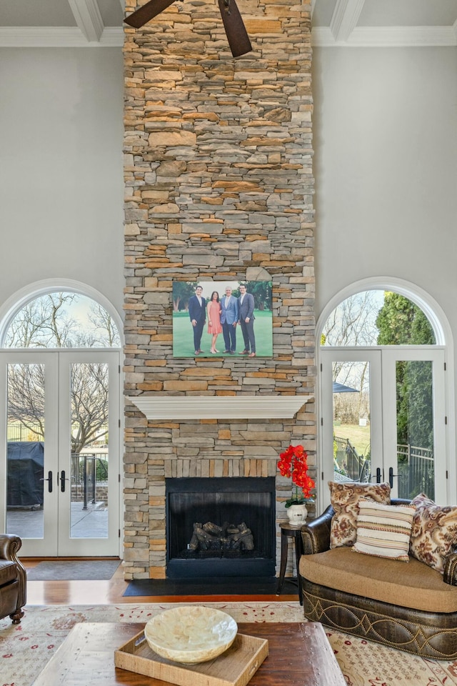 living area featuring a stone fireplace, french doors, and ornamental molding