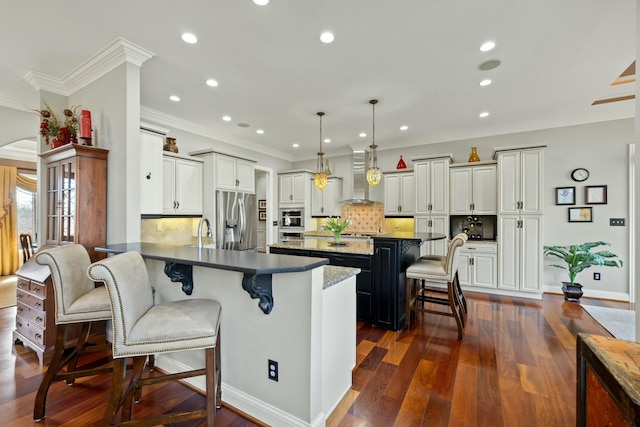 kitchen featuring crown molding, a kitchen bar, stainless steel appliances, wall chimney exhaust hood, and dark wood-style flooring