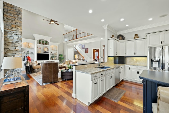 kitchen with wood finished floors, a peninsula, a sink, white cabinets, and appliances with stainless steel finishes