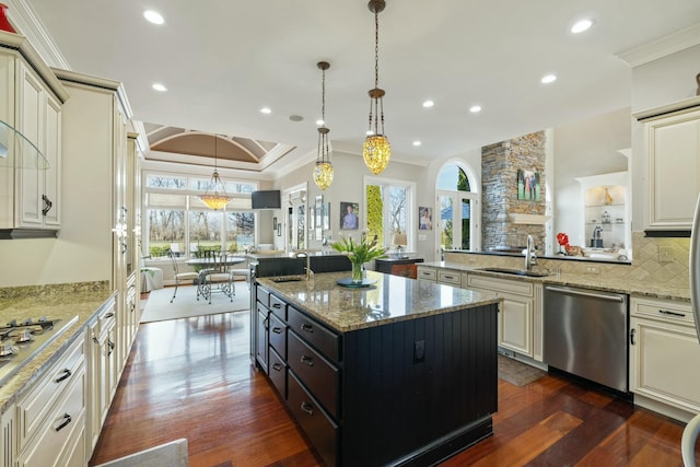 kitchen featuring ornamental molding, open floor plan, appliances with stainless steel finishes, and a sink