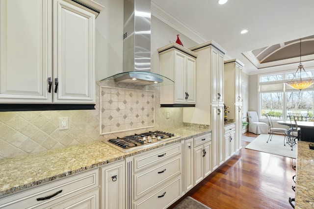 kitchen with ornamental molding, dark wood-style floors, stainless steel gas stovetop, wall chimney exhaust hood, and light stone countertops