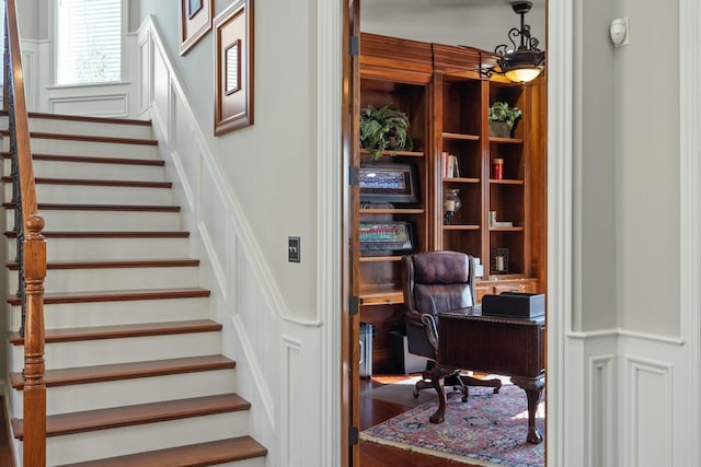 stairway featuring a decorative wall and wainscoting