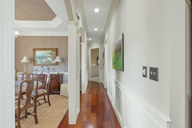 hallway featuring a wainscoted wall, wood finished floors, crown molding, a decorative wall, and decorative columns