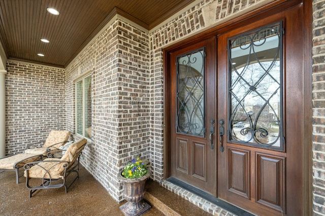 view of exterior entry featuring covered porch and brick siding