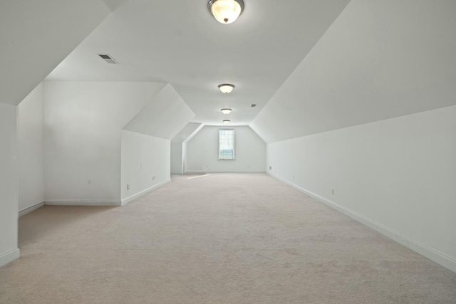 additional living space with visible vents, light colored carpet, baseboards, and lofted ceiling