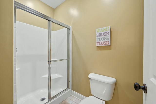 bathroom with tile patterned floors, baseboards, toilet, and a shower stall