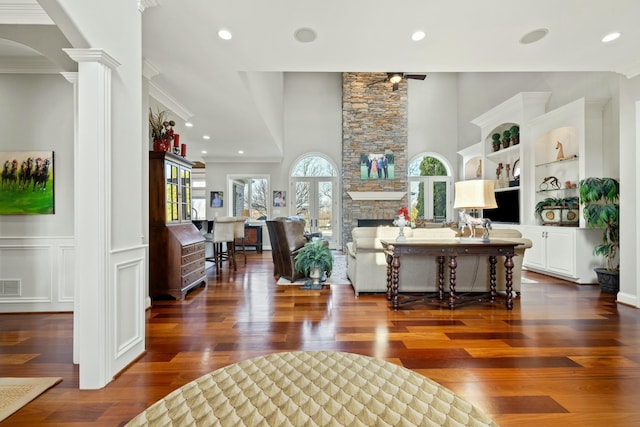 living room with dark wood-style floors, visible vents, decorative columns, a fireplace, and ornamental molding