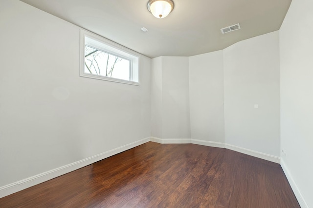 empty room with wood finished floors, visible vents, and baseboards