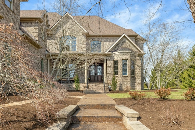 view of front facade featuring brick siding and roof with shingles