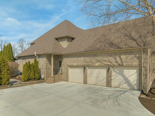 view of front of house featuring driveway, brick siding, an attached garage, and a shingled roof