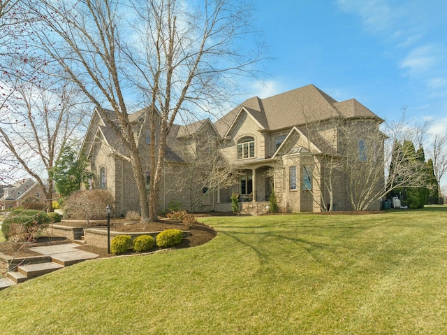 french country home featuring brick siding and a front lawn