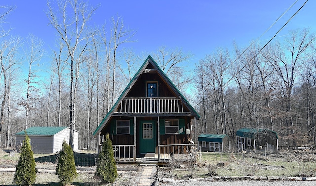 a-frame style home with a balcony, a porch, and an outbuilding