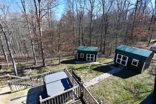 view of yard with a storage shed, a wooden deck, a wooded view, and an outdoor structure