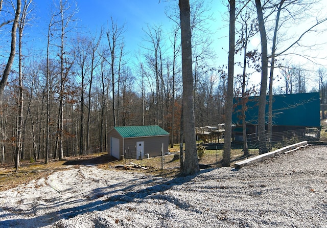 exterior space with an outbuilding, a forest view, fence, and driveway