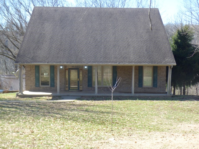 view of front of property featuring brick siding, roof with shingles, and a front yard