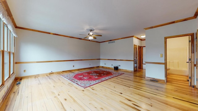 unfurnished room with crown molding, visible vents, ceiling fan, baseboards, and hardwood / wood-style flooring