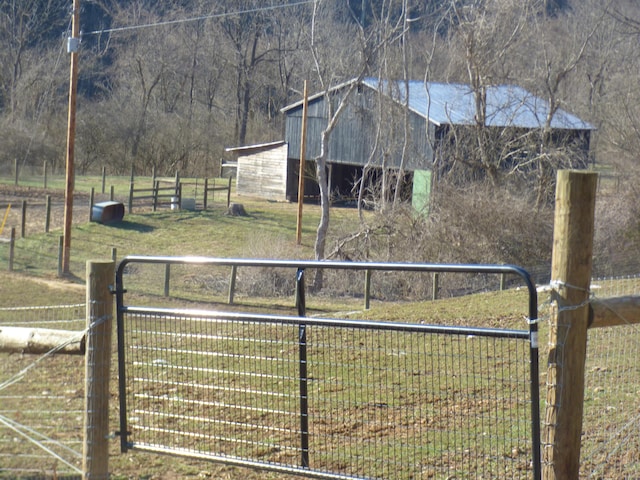 exterior space featuring a yard, a rural view, an outdoor structure, and fence