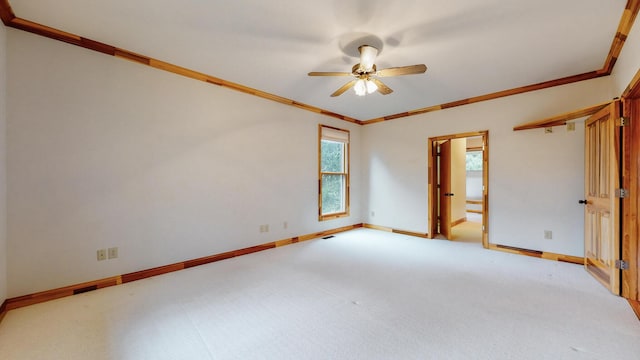 spare room featuring baseboards, carpet floors, a ceiling fan, and crown molding