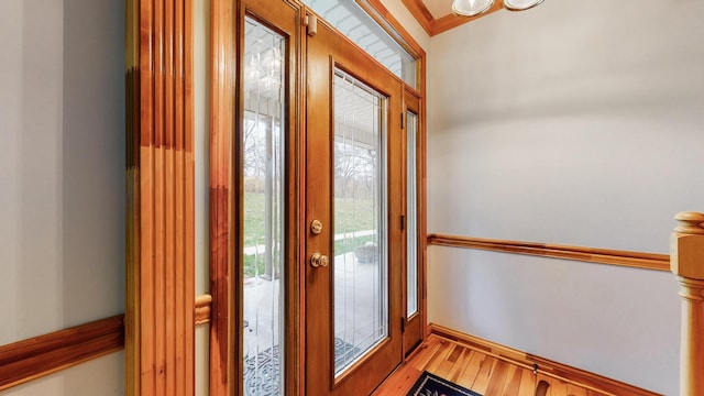 entryway featuring light wood-type flooring, crown molding, and baseboards