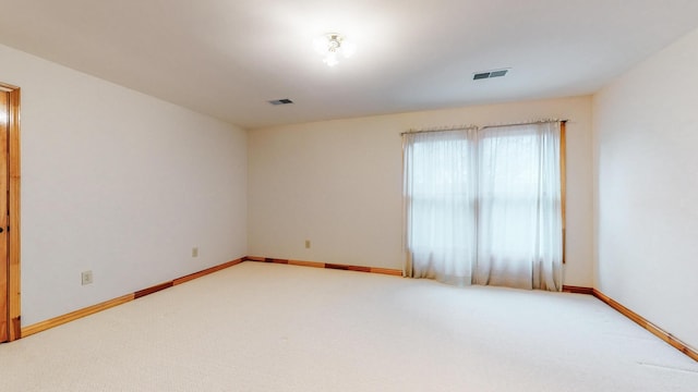 carpeted spare room featuring visible vents and baseboards