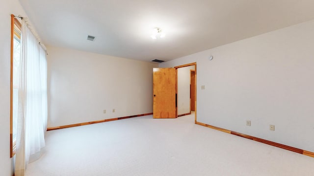 empty room with light carpet, visible vents, and baseboards