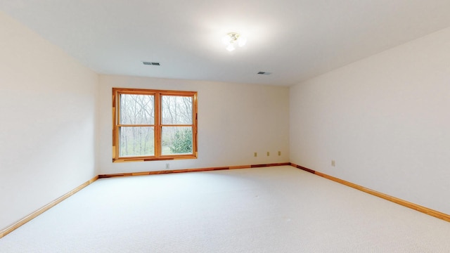 carpeted spare room featuring visible vents and baseboards