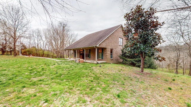 view of front of property with covered porch, a front yard, and brick siding