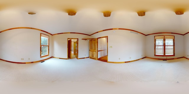 spare room with lofted ceiling, carpet floors, visible vents, baseboards, and ornamental molding