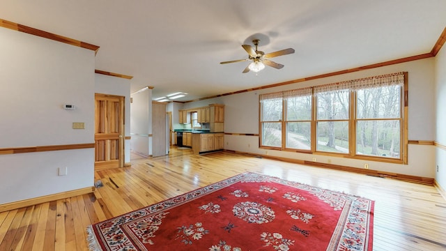 living room featuring ornamental molding, light wood-type flooring, a ceiling fan, and baseboards